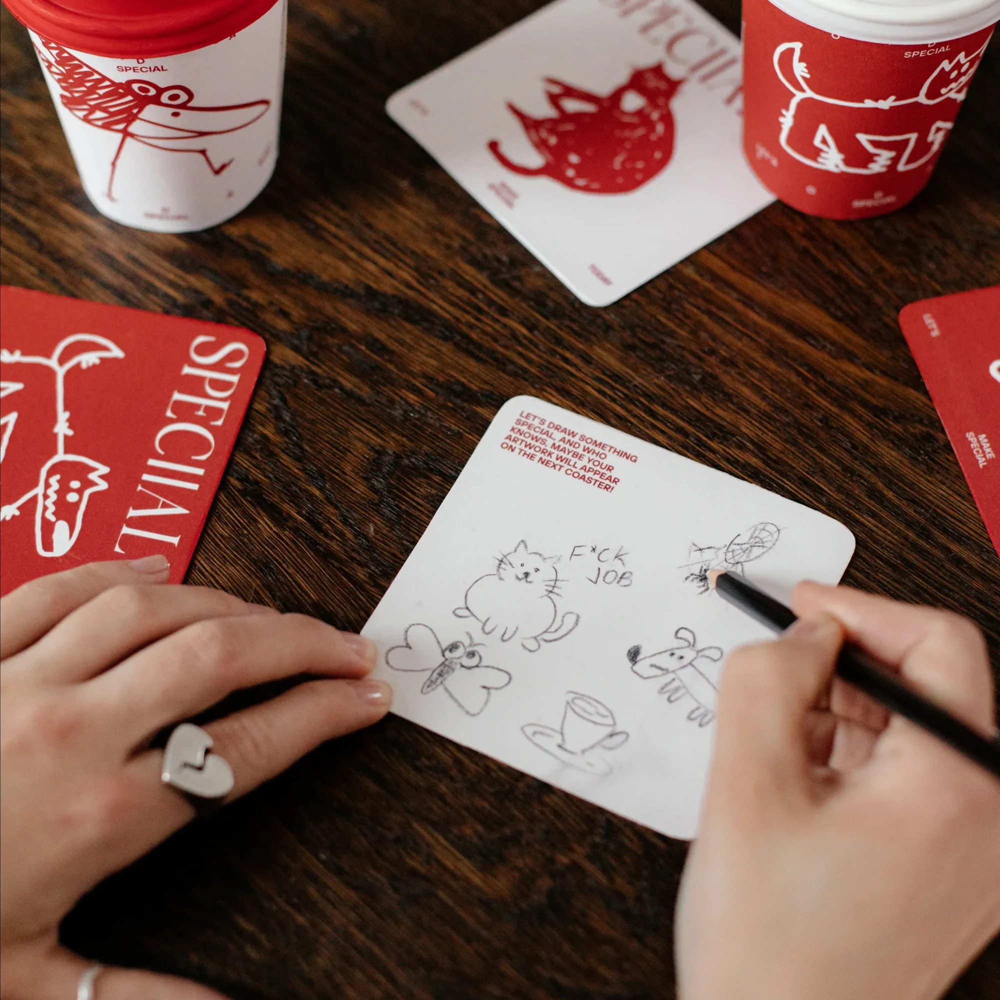 A customer doodling on a coaster at the table